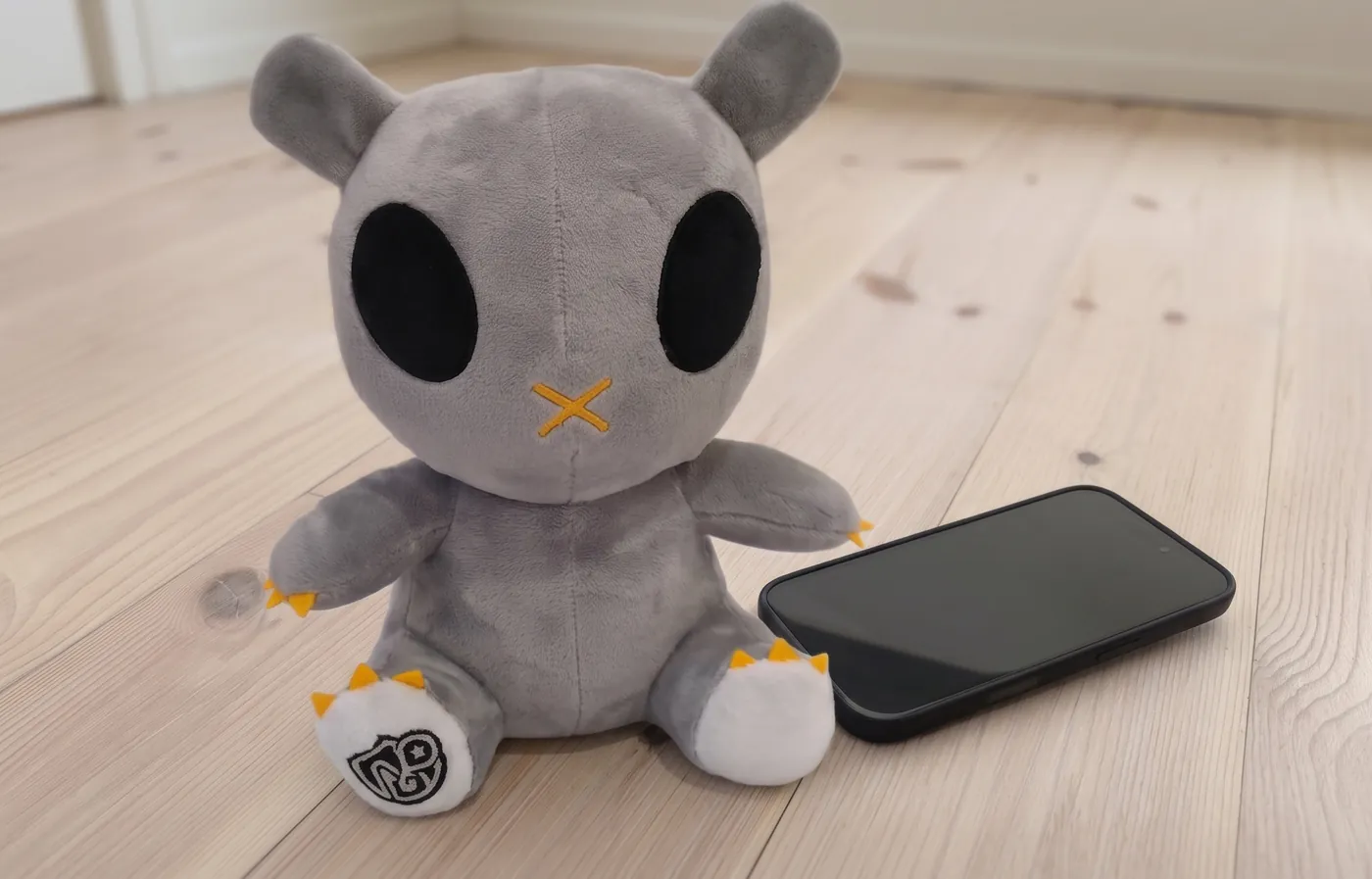 Ravyn next to a phone on a pine floor